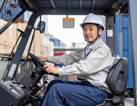 フォークリフトを運転する男性作業員 フォークリフトを運転する男性作業員の写真
