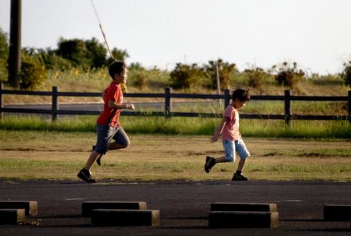＜素材＞夕暮れの公園を走る男の子 子供,兄弟,ジョギングの写真素材