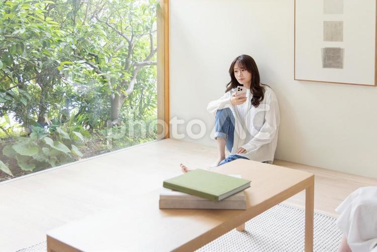 床に座りスマートフォンを使う女性 スマートフォン,座る,検索の写真素材