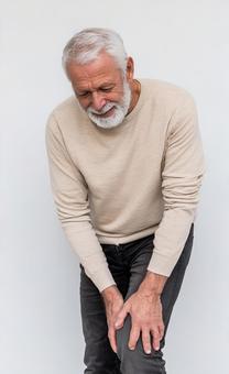 痛む膝を抑える男性の写真