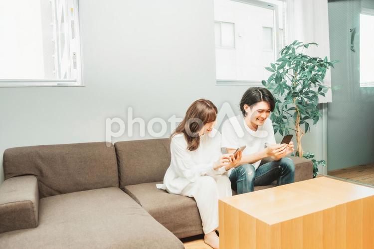 部屋でスマホを使う男女 スマホ,カップル,夫婦の写真素材
