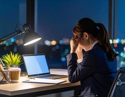 残業が終わらず頭を抱える女性 残業が終わらず頭を抱える女性の写真