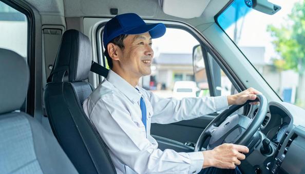 トラックを運転する男性ドライバーの横顔 トラックを運転する男性ドライバーの横顔の写真