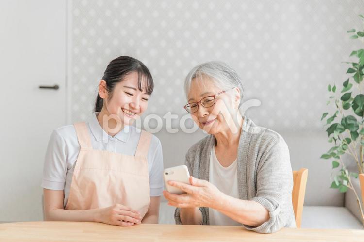 スマホを使う高齢者と女性スタッフ 高齢者,スマホ,スマートフォンの写真素材