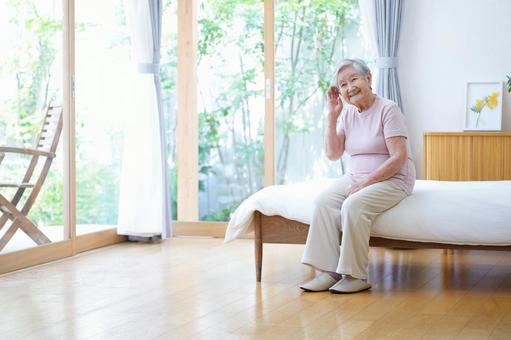 ベッドに座り笑顔で耳に手を当てる高齢女性 女性,ベッド,座るの写真素材