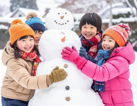 雪だるまを作って喜ぶ子供の冬の屋外風景の写真