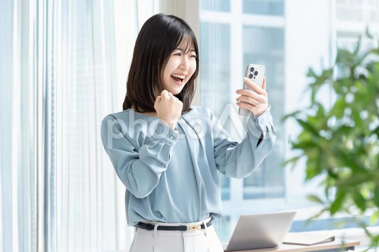 スマホを見て喜ぶ女性・ビジネスウーマン 女性,スマホ,スマートフォンの写真素材