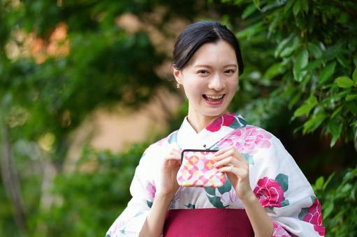 浴衣姿の女性が笑顔で立つ 女性,浴衣,財布の写真素材
