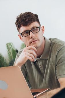 椅子に座って手に持ってノートパソコンを使っている男性 男性,外国人,欧米人の写真素材