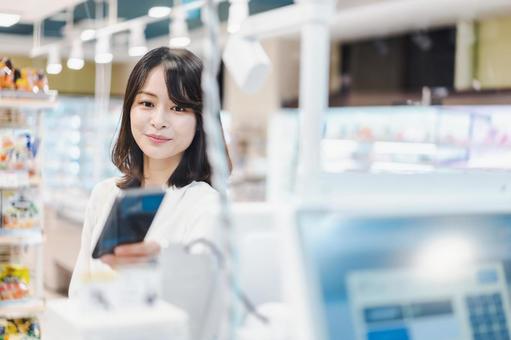 スーパーでスマホ決済を使う若い女性 スーパーでスマホ決済を使う若い女性 セルフレジ,ポイ活,お得の写真素材