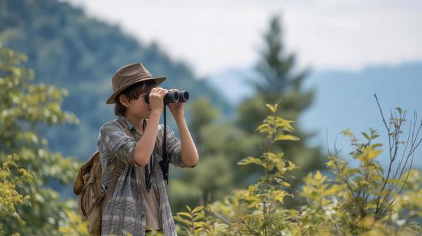 山で双眼鏡をのぞく少年の写真