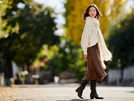 秋の並木道を歩く女性の写真