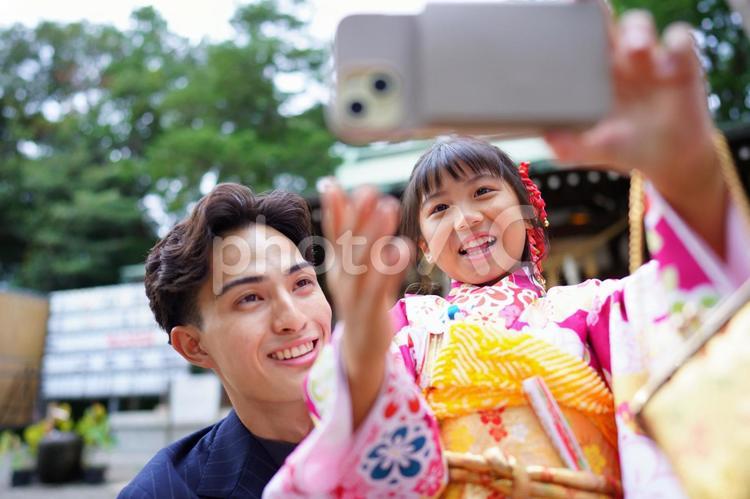 神社を背景に家族で記念撮影を楽しむ姿 七五三,お参り,七五三参りの写真素材