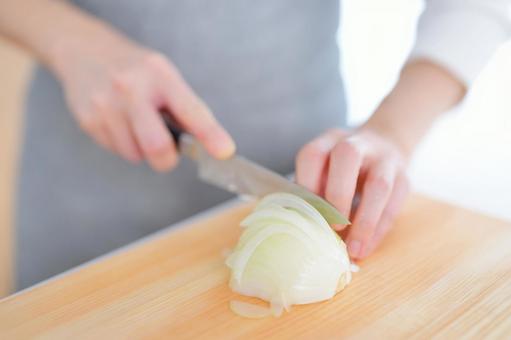 玉ネギをカットしている手の写真