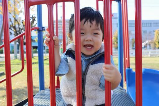 笑顔で滑り台のてっぺんにいる男の子 笑顔で滑り台のてっぺんにいる男の子の写真