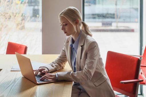 窓のあるオフィスでノートパソコンを使うビジネスウーマン ビジネスウーマン,ビジネス,女性の写真素材