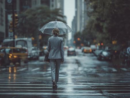 都会の雨の中を歩く女性ビジネスパーソン 都会の雨の中を歩く女性ビジネスパーソンの写真