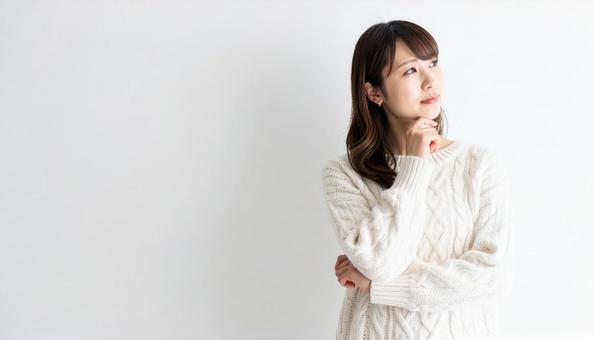 考え事をする白いニットの女性ポートレートの写真