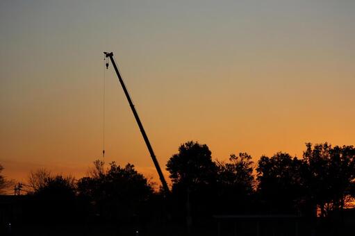 シルエットの森とクレーンとオレンジの夕空 シルエット,森,クレーンの写真素材