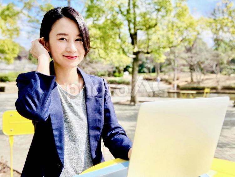 自然が豊かな公園で仕事をする笑顔の女性 パソコン,女性,pcの写真素材
