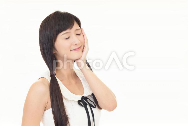 頬に手を当てて目を閉じる女性 女性,笑顔,微笑むの写真素材