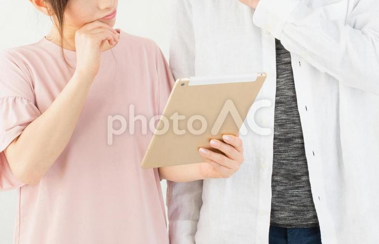 タブレットを見て首をかしげる男女 タブレット,考える,疑問の写真素材