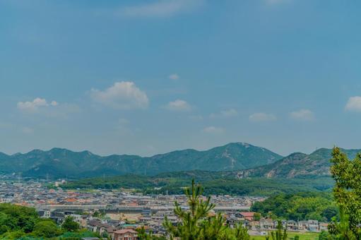 青空の下に広がる町並みと緑の山々の夏景色 青空の下に広がる町並みと緑の山々の夏景色の写真