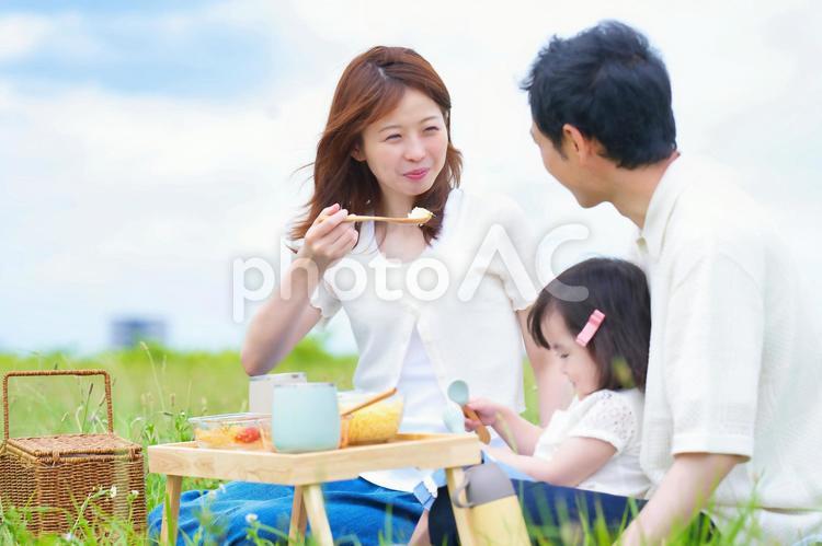 ご飯をスプーンですくって微笑む女性と家族 男性,女性,女の子の写真素材