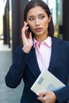 アジア人ビジネスウーマンがオフィス街で電話する ビジネスウーマン,ビジネス,女性の写真素材