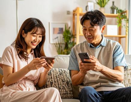 自宅でスマホを操作する親子 自宅でスマホを操作する親子の写真