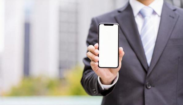 携帯画面を見せて笑うビジネスマンの写真