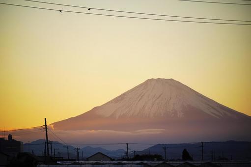淡い夕焼け空にそびえる富士山の写真