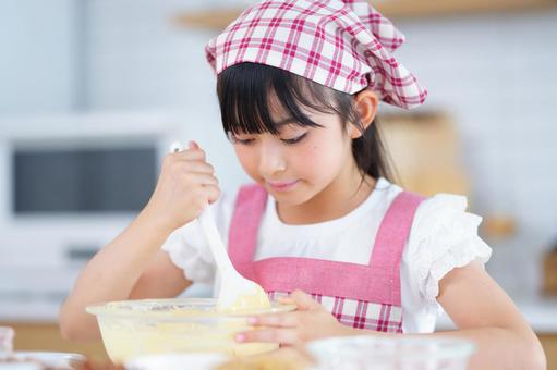 真剣な表情で生地をかき混ぜる女の子 女の子,小学生,日本人の写真素材