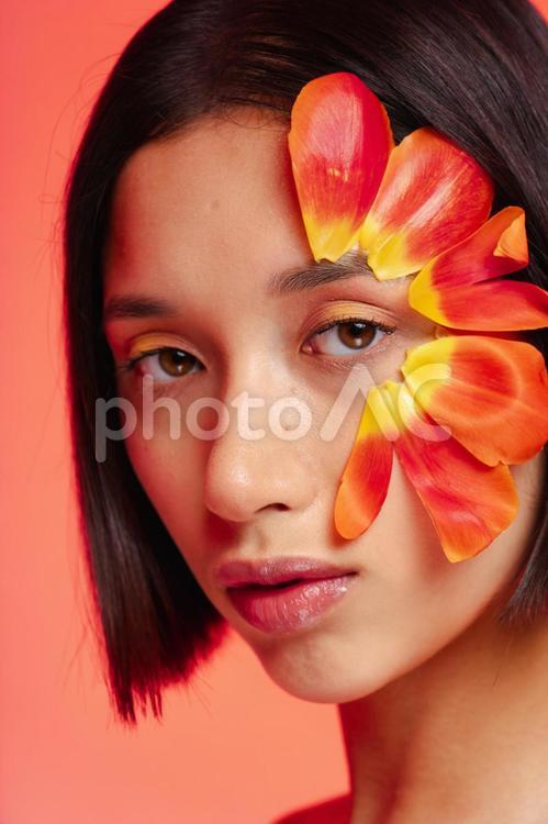 赤い花びらを顔に付けた女性の顔 女性,フラワーメイク,花びらの写真素材