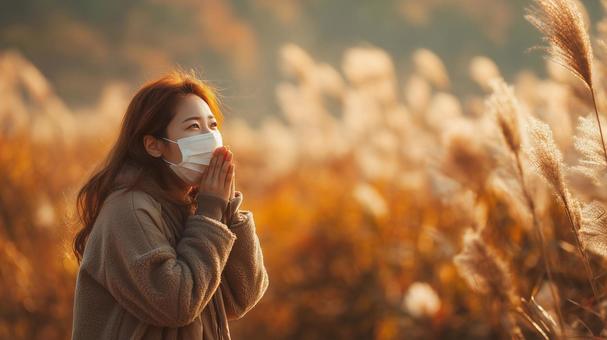秋風に揺れるススキとマスク姿の女性 秋風に揺れるススキとマスク姿の女性の写真