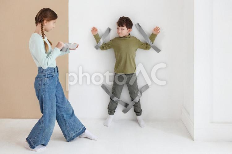 ガムテープで貼り付けて遊ぶ姉弟 男の子,女の子,姉弟の写真素材