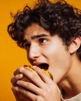 美味しそうにハンバーガーを食べる若者 美味しそうにハンバーガーを食べる若者の写真