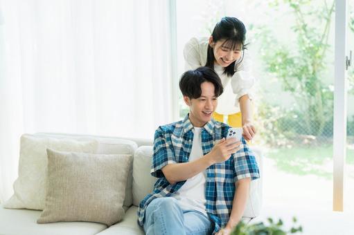 リビングでスマホを見るカップル スマホ,笑顔,カップルの写真素材