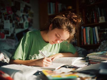 部屋で勉強に取り組む学生のポートレートの写真