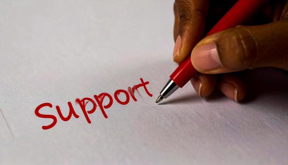 文字「Support」と赤ペンで書く手元 文字「Support」と赤ペンで書く手元の写真