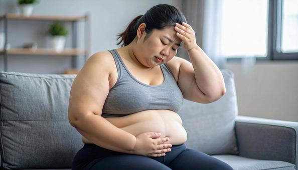 肥満で疲れやすく、額に手をやる女性 肥満で疲れやすく、額に手をやる女性の写真