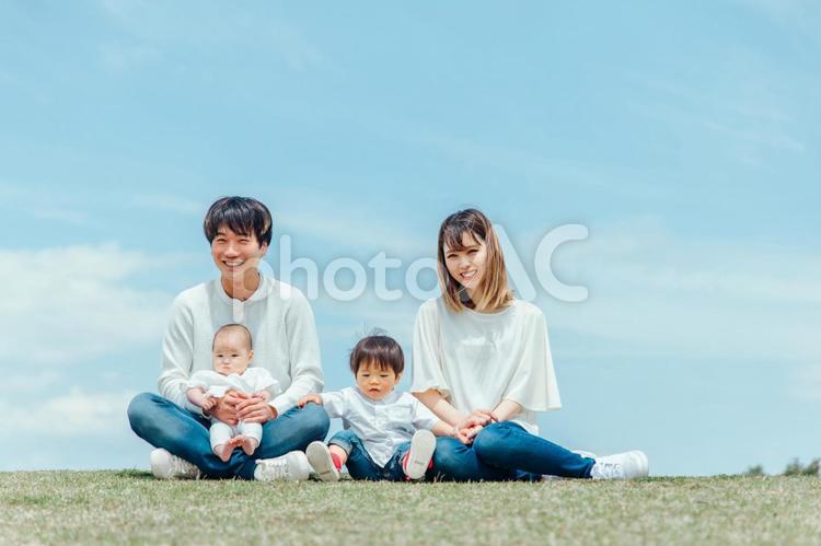 空と芝生に座る家族・ファミリー（4人） 家族,親子,赤ちゃんの写真素材