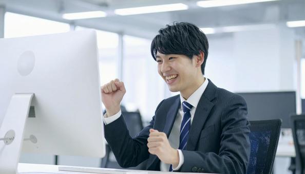 オフィスで喜ぶビジネスマン オフィスで喜ぶビジネスマンの写真