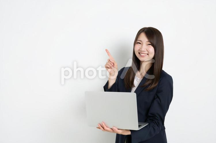 パソコンを持って指差ししているビジネスウーマン（コピースペース） ビジネス,女性,スーツの写真素材