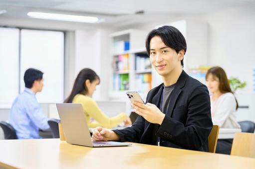 パソコンの前でスマホを確認する男性社員 ビジネスマン,スマホ,ノートパソコンの写真素材