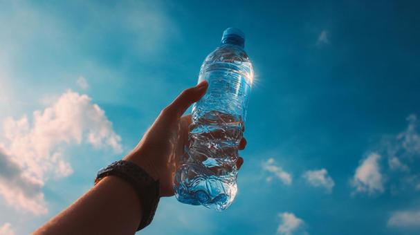 青空に掲げられたペットボトルの水の写真