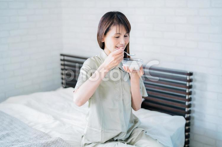 寝室でヨーグルトを食べる女性（笑顔） ヨーグルト,乳酸菌,菌活の写真素材