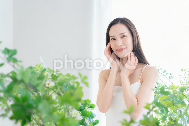 緑の中でスキンケアをする若い女性 ビューティー,女性,スキンケアの写真素材