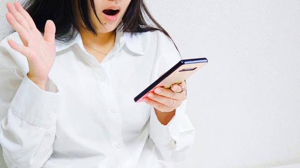 スマホを見て驚く女性 スマホを見て驚く女性 びっくり仰天,驚く,スマホの写真素材