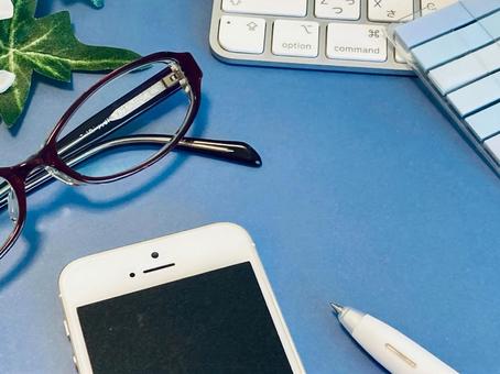 机の上のスマホ、眼鏡、PC（青背景） ビジネス,仕事,打ち合わせの写真素材